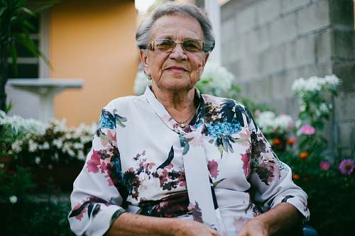 potted plant woman wearing white and multicolored floral top front of flower garden vase